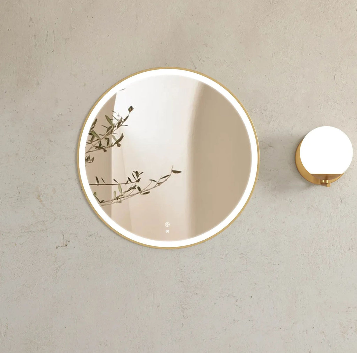 Round wall mirror with gold frame on a light gray wall