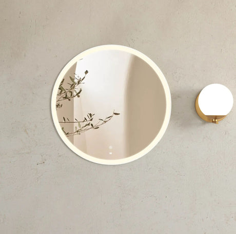 Round wall mirror with a light fixture on a beige wall