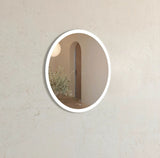 Round mirror with a decorative frame on a beige wall