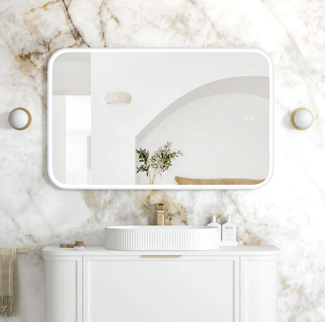 Bathroom vanity with mirror and decorative items against a marble wall.