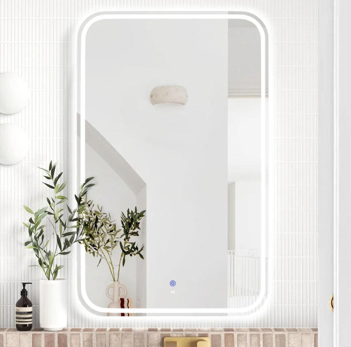 Rectangular mirror on a bathroom wall with plants and decor.