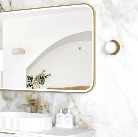 Bathroom with a modern mirror, sink, and decorative elements on a marble wall.