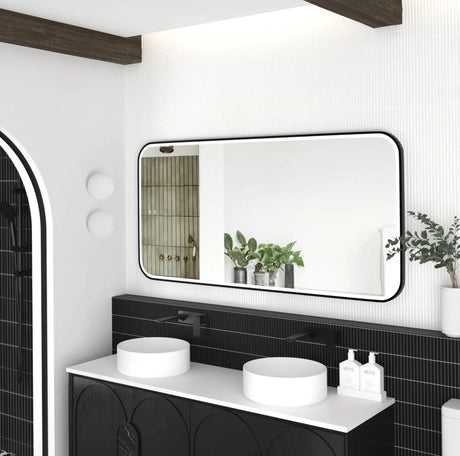 Bathroom vanity with a large mirror, black tiles, and white fixtures.