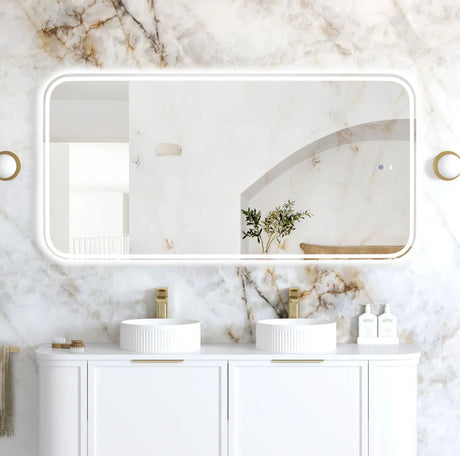 Bathroom with marble walls, white vanity, and large mirror.