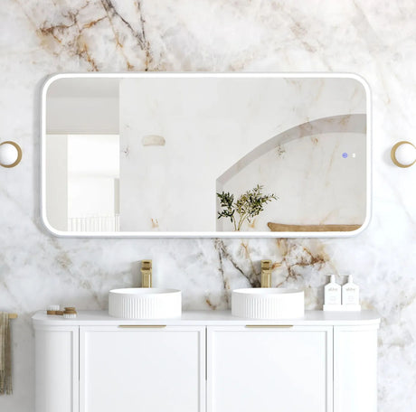 Bathroom vanity with two sinks, a large mirror, and decorative elements on a marble wall.