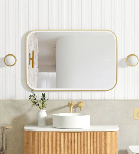Bathroom with wooden vanity, white sink, and gold fixtures.