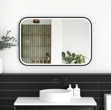 Bathroom with a large mirror reflecting a shower area, black tiles, and a white sink.