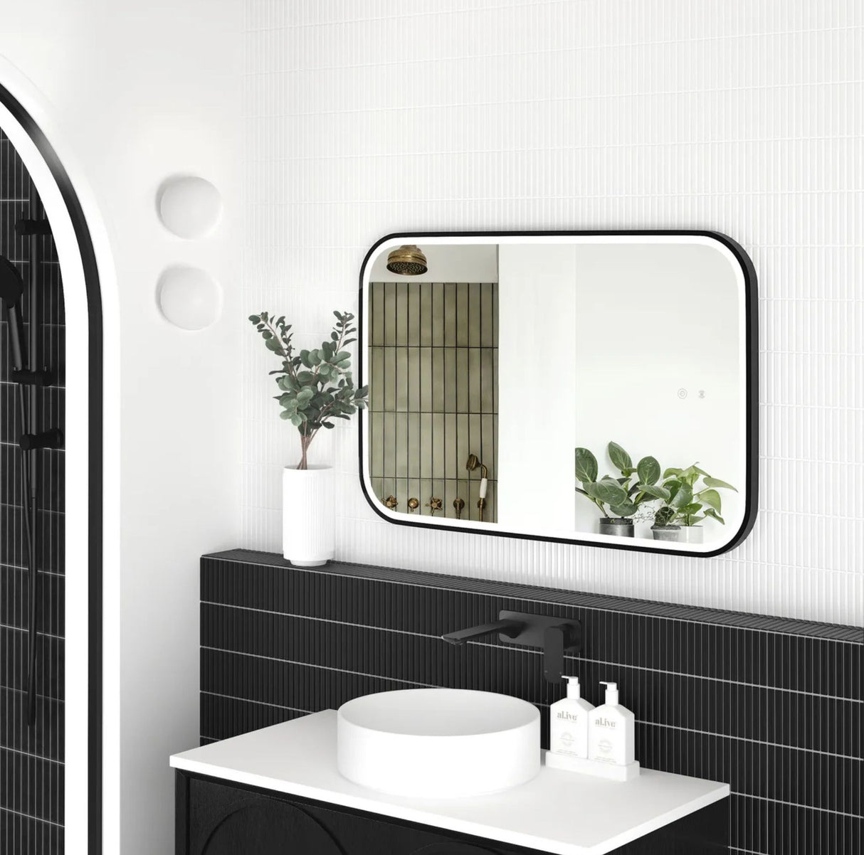 Modern bathroom with black tiles, white sink, and decorative mirror.