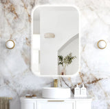 Bathroom with a large mirror, sink, and decorative elements on a marble wall.