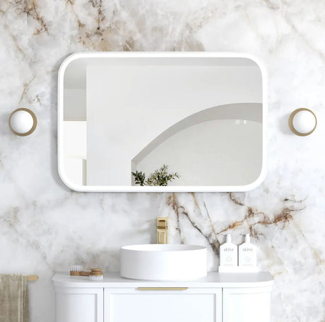 Bathroom with white sink, mirror, and decorative elements on a marble wall.