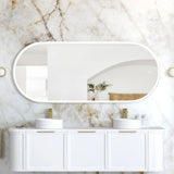 Bathroom vanity with two sinks and a large mirror against a marble wall.