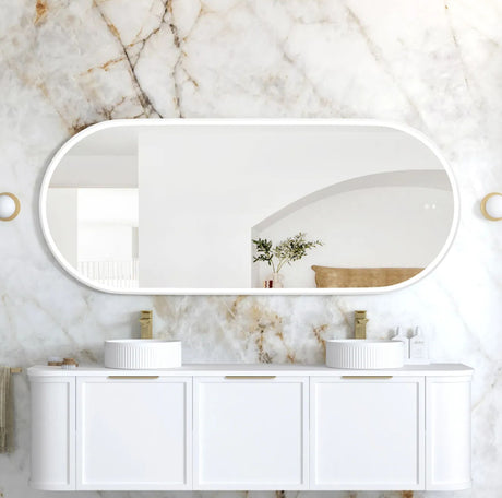 Bathroom vanity with two sinks and a large mirror against a marble wall.