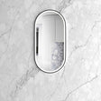 Oval mirror with black frame on a marble wall