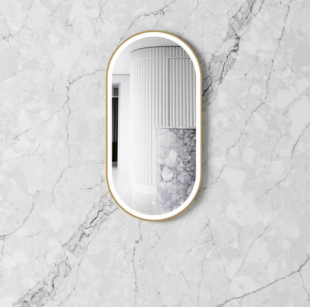 oval mirror with gold frame on a marble wall