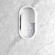oval mirror with white frame on a marble wall