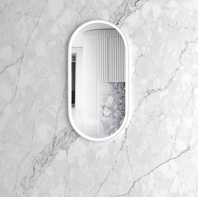oval mirror with white frame on a marble wall