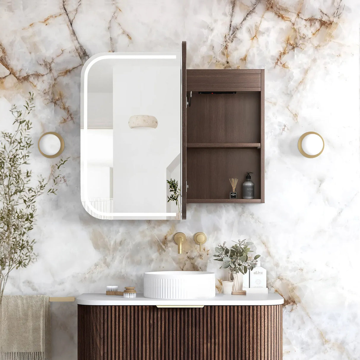 A modern bathroom vanity setup with a dark brown wood cabinet featuring an integrated illuminated mirror and open storage shelf, mounted on a white marble wall above a matching wood vanity with a white vessel sink.