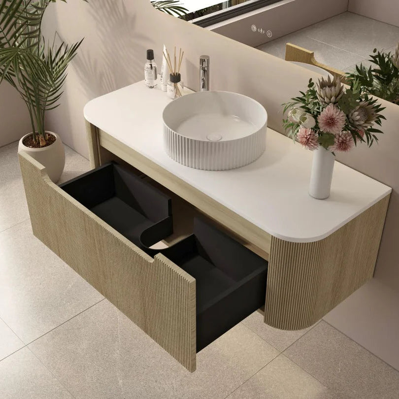 Bathroom vanity with a sink, flowers, and toiletries on a light-colored floor.