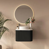 Modern bathroom setup with round mirror, black vanity, and decorative elements.