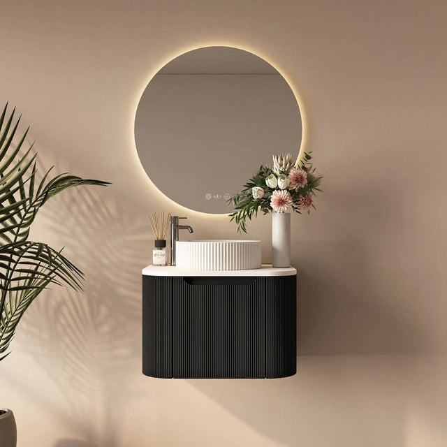 Modern bathroom setup with round mirror, black vanity, and decorative elements.