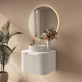 Modern bathroom setup with a round mirror, sink, and decorative plant.