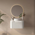 Modern bathroom setup with a white vanity, round mirror, and decorative elements on a beige wall.