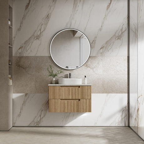 Bathroom with marble walls, wooden vanity, and round mirror.
