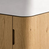Close-up of a corner cabinet with light oak wood grain doors and a white countertop.