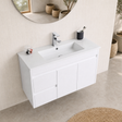 A modern white wall-mounted bathroom vanity with an integrated rectangular sink, chrome faucet, and three cabinet doors, shown in a clean beige-toned bathroom setting with a round mirror and small decor items.