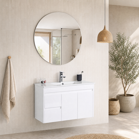 A modern bathroom vanity setup featuring a white wall-mounted cabinet with an integrated white sink, a round backlit mirror, a chrome faucet, and a black cup holder, set against a beige tiled wall with a hanging towel and a potted plant.