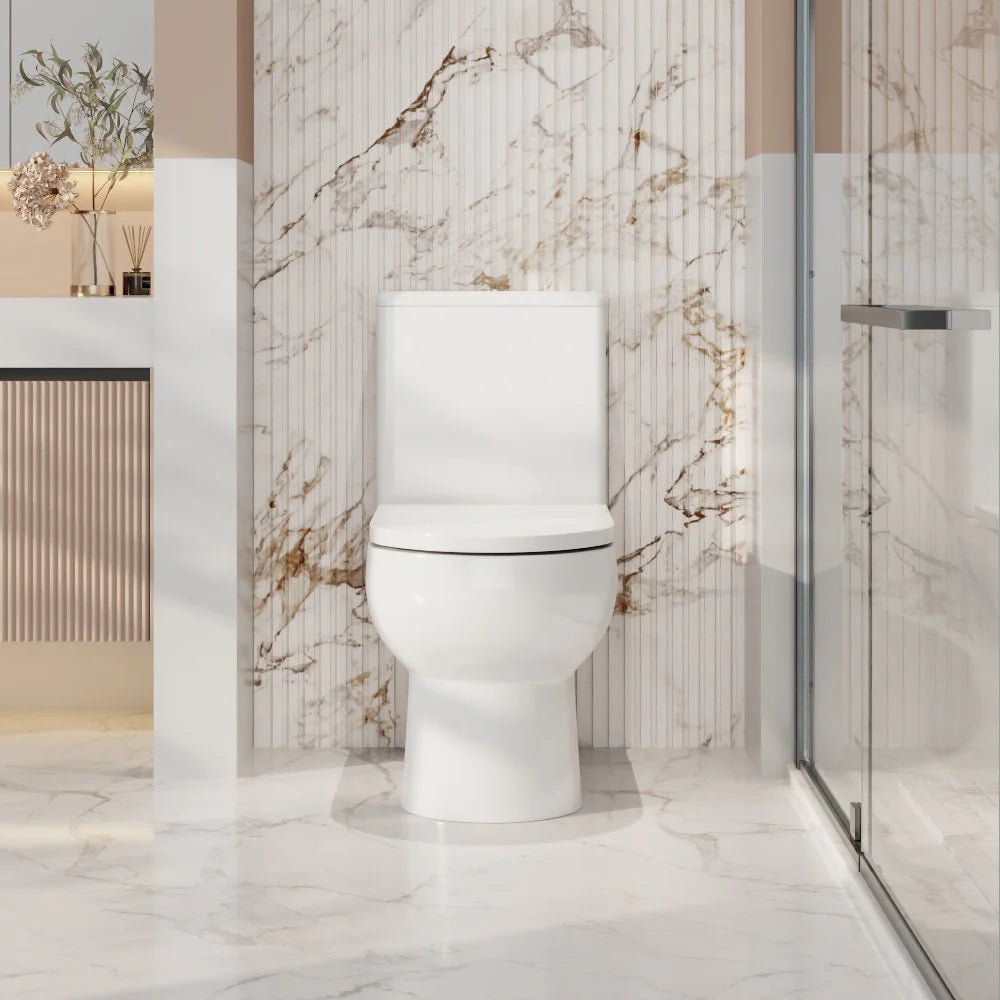 Modern toilet in a bathroom with marble walls and a glass shower enclosure.