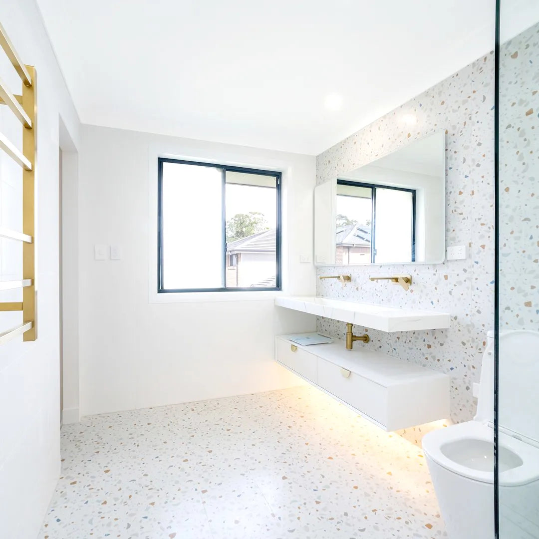 Modern bathroom with white tiles, a window, and a toilet.
