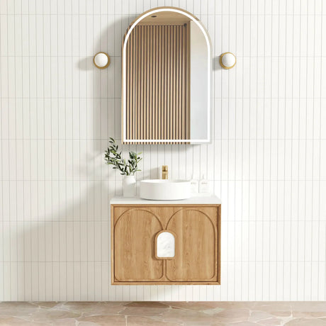 Bathroom vanity with wooden cabinet, round mirror, and decorative elements on a tiled wall.