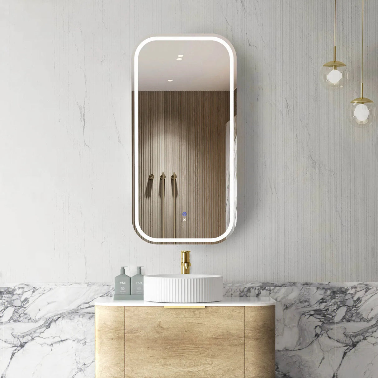 Bathroom with a vanity, sink, and illuminated mirror on a marble wall.
