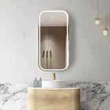 Bathroom with a vanity, sink, and illuminated mirror on a marble wall.