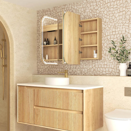 Bathroom with wooden vanity, mirror, and toilet against a stone wall.