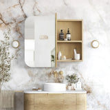 Modern bathroom with wooden vanity, mirror, and shelves against a marble wall.