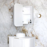 Bathroom with white vanity, sink, and cabinet against a marble wall.