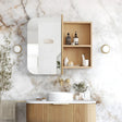 Bathroom with wooden vanity, mirror, and shelves against a marble wall.