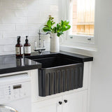 Modern kitchen with black farmhouse sink, white cabinets, and black and white patterned floor.