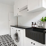 Modern kitchen with black countertop, white appliances, and geometric floor pattern.