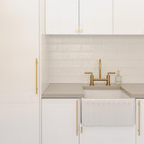 Modern kitchen with white cabinets, gold fixtures, and a tiled backsplash.