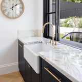 Modern kitchen with black cabinets, white marble countertop, and a clock on the wall.