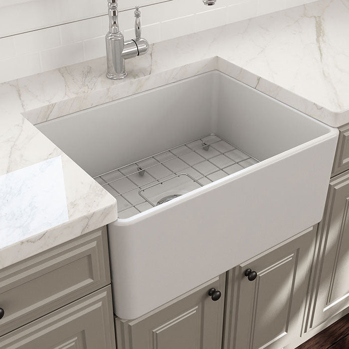 White farmhouse sink in a kitchen setting with marble countertop and cabinets.
