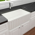 White farmhouse sink with black marble countertop in a kitchen setting