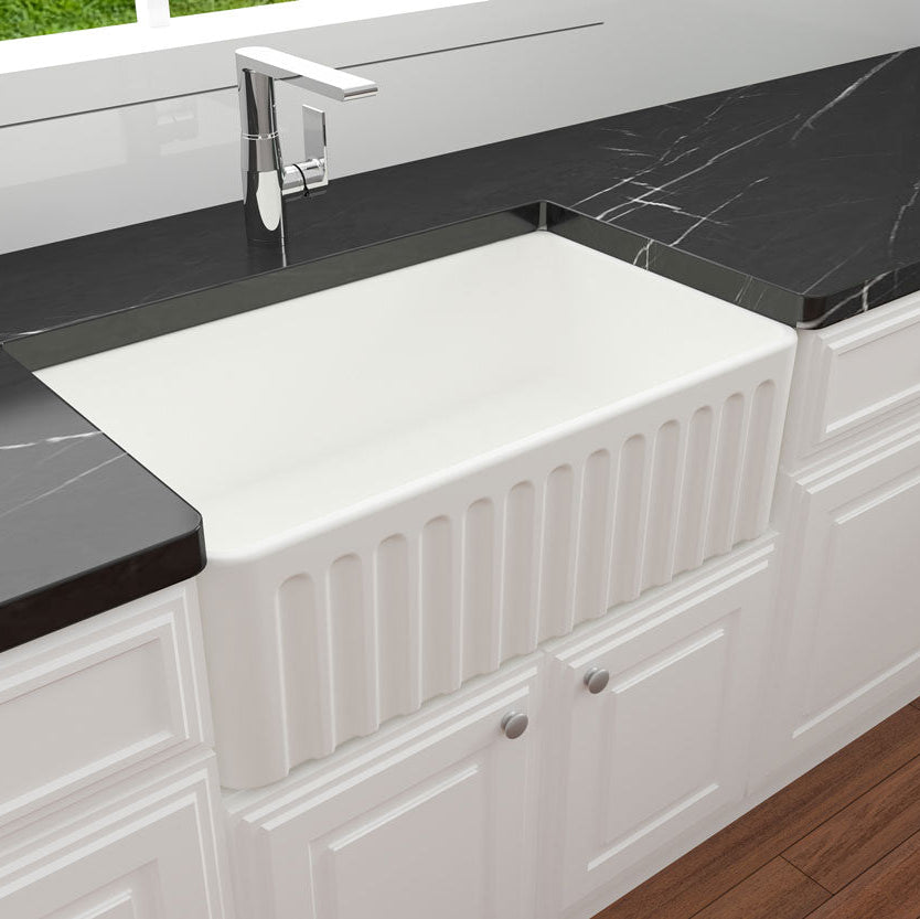 White farmhouse sink with black marble countertop in a kitchen setting