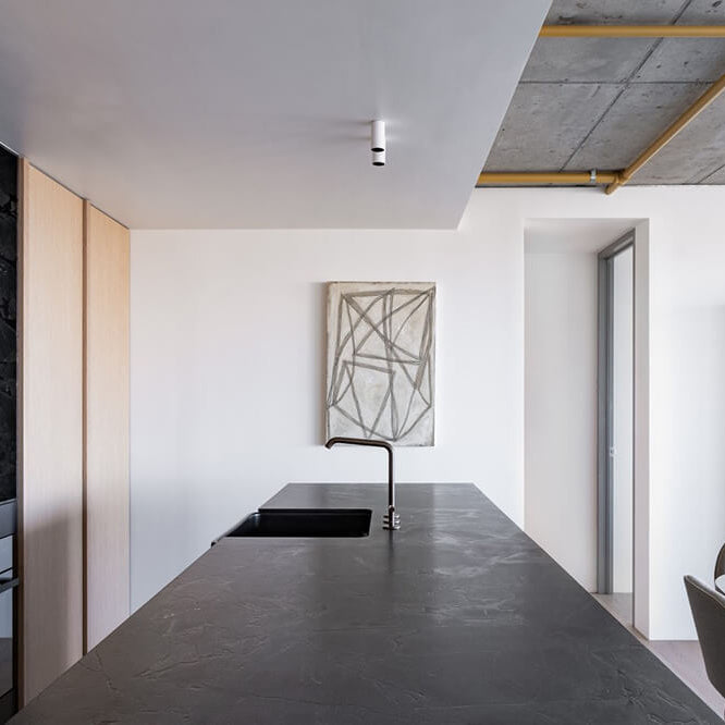 Modern kitchen with concrete countertop, white walls, and minimal decor.