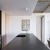 Modern kitchen with concrete countertop, white walls, and minimal decor.