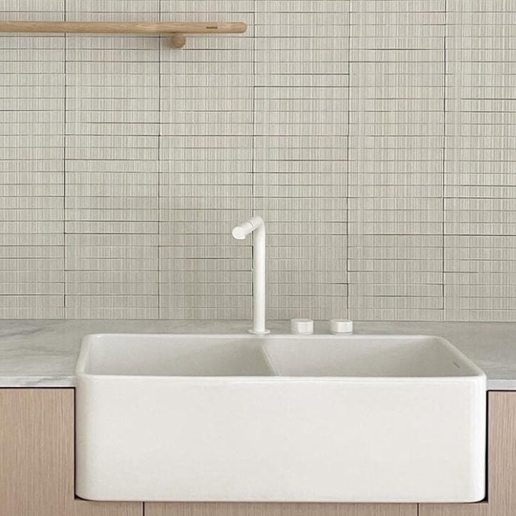 Modern kitchen with a white sink against a tiled wall.