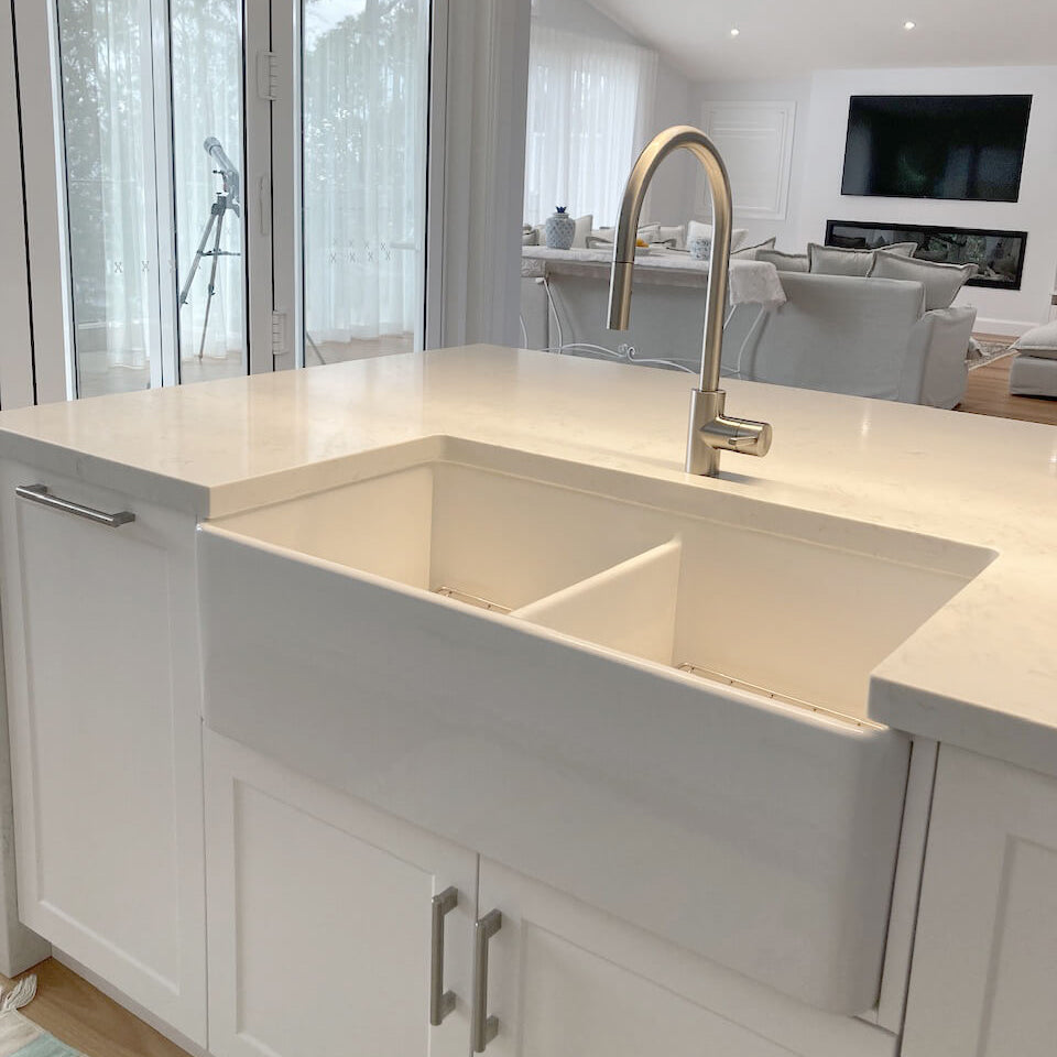 Modern kitchen with a large farmhouse sink and white cabinets.